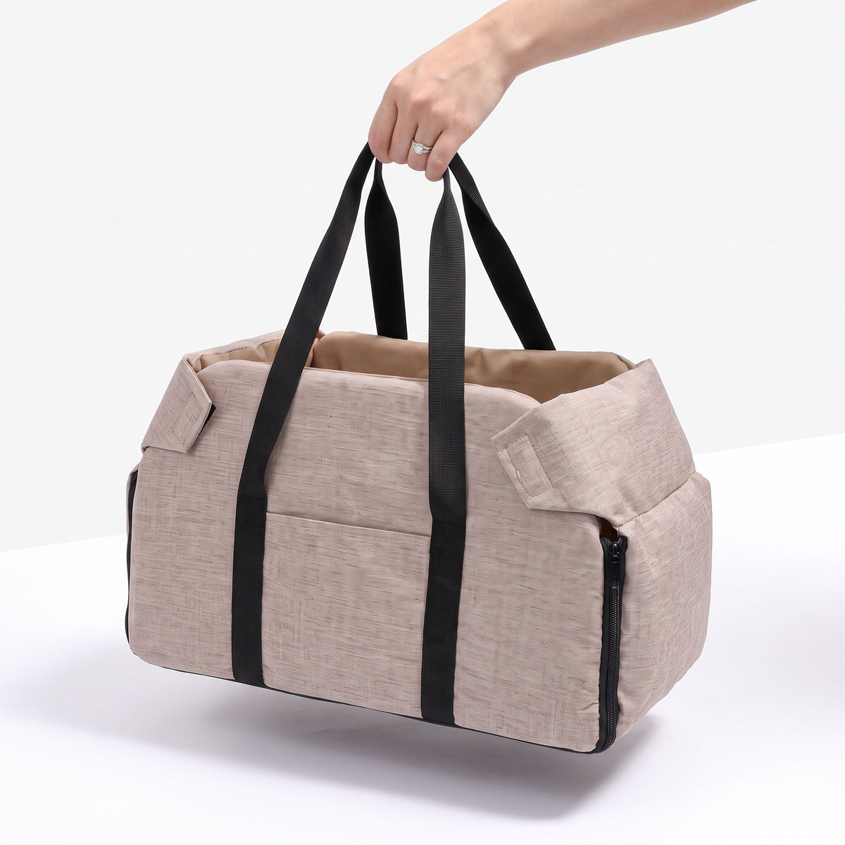Hand holding the Console Dog Car Seat carrier by its handles