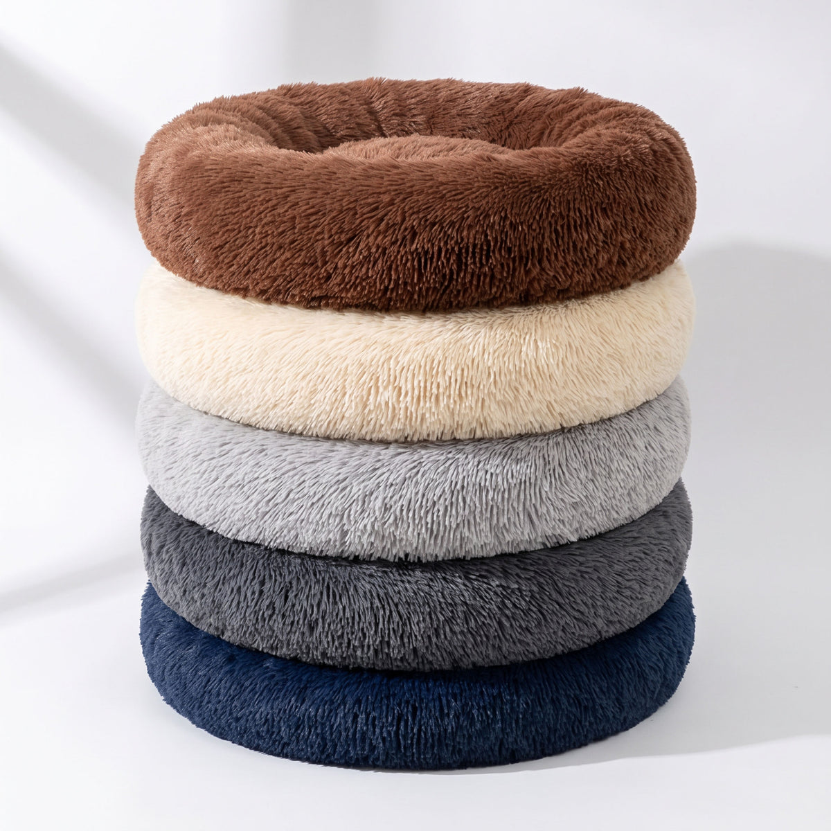 All five colourways of the round plush cat bed stacked together - charcoal, taupe, cream, blush and brown