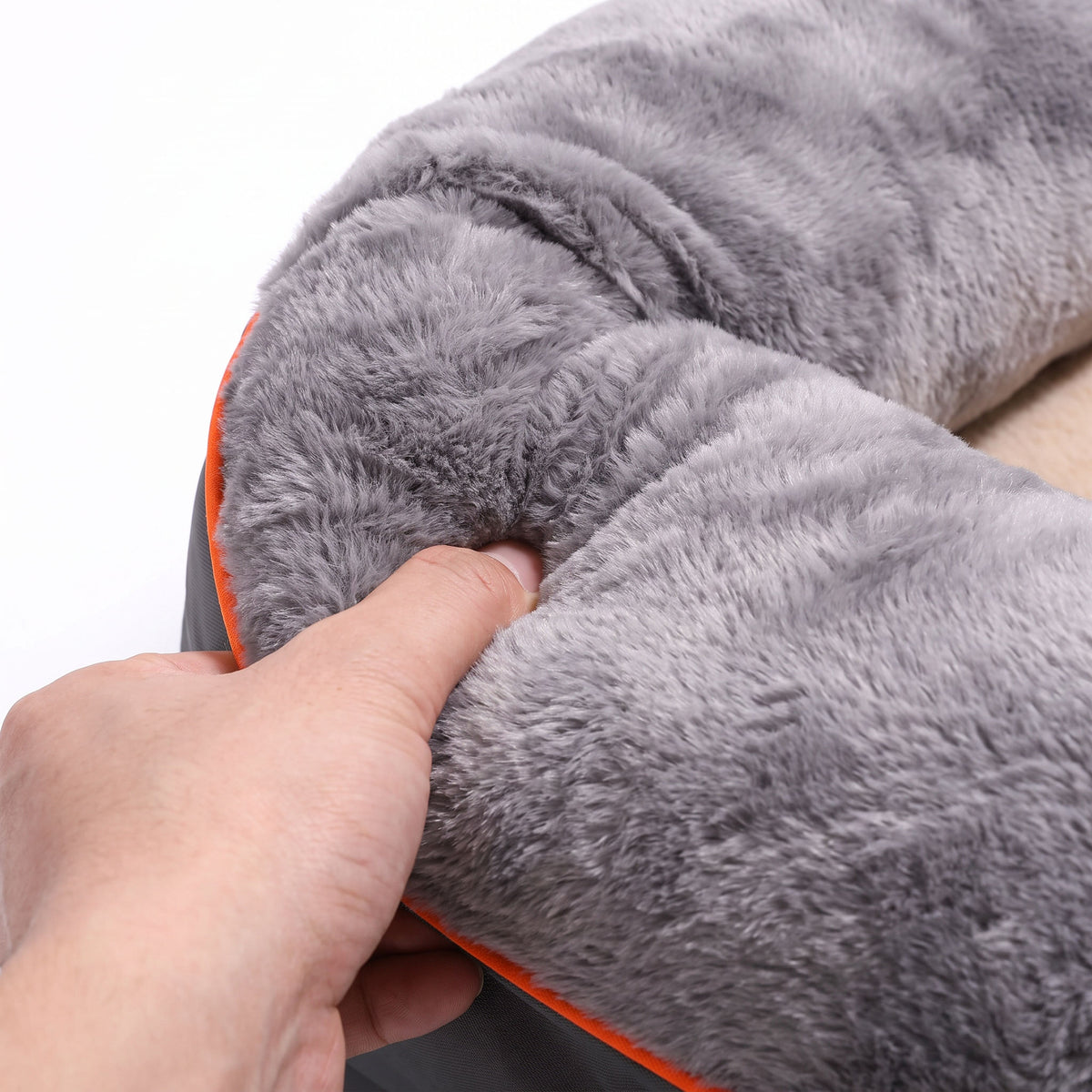 Close-up of a hand pressing into the padded bolster rim of the dog sofa bed