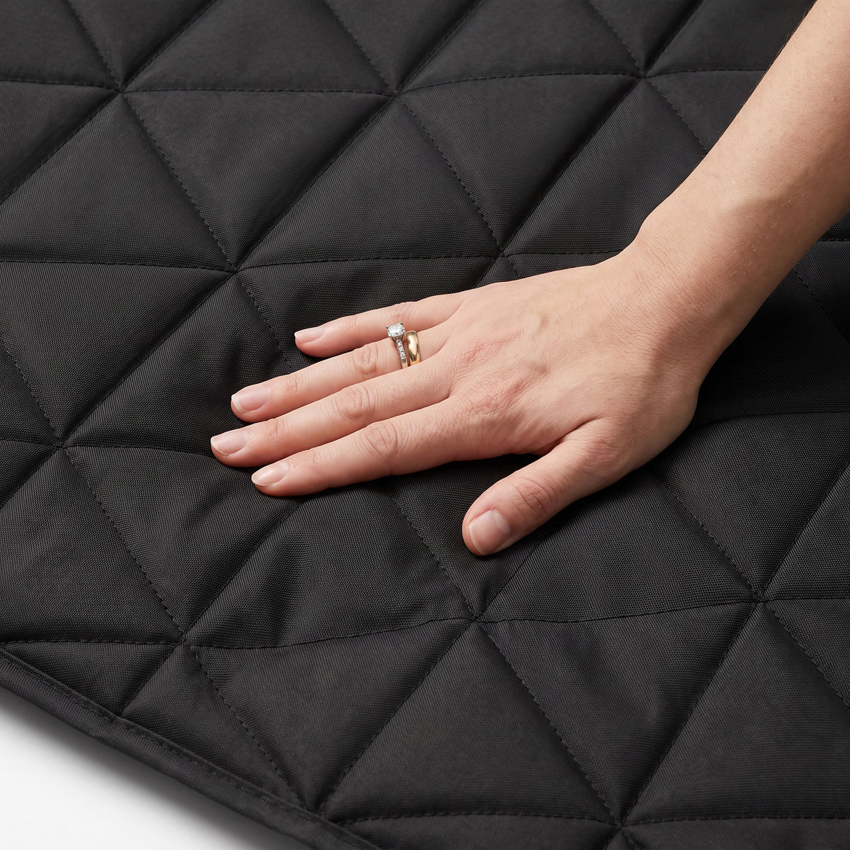 Close-up of a hand pressing into the quilted fabric of the dog car seat cover