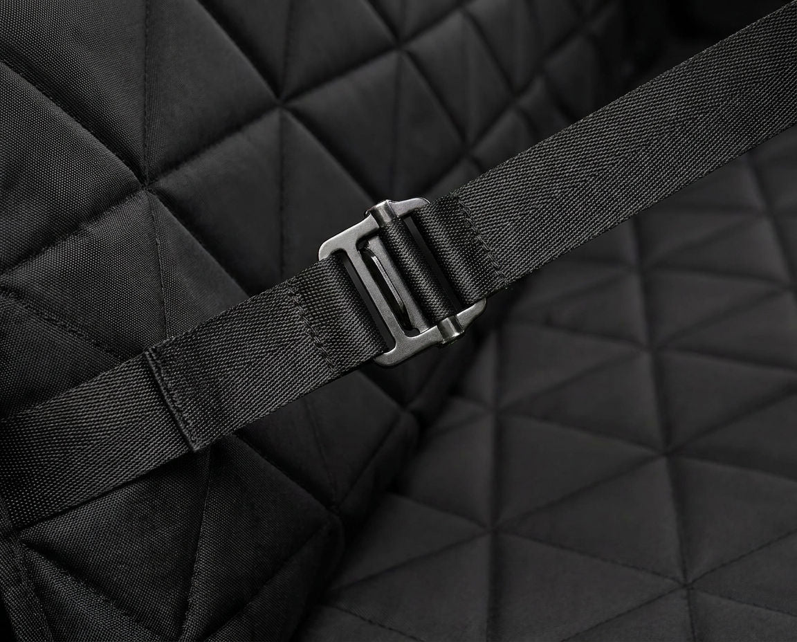 Webbing strap threaded through its metal buckle on the quilted car seat cover