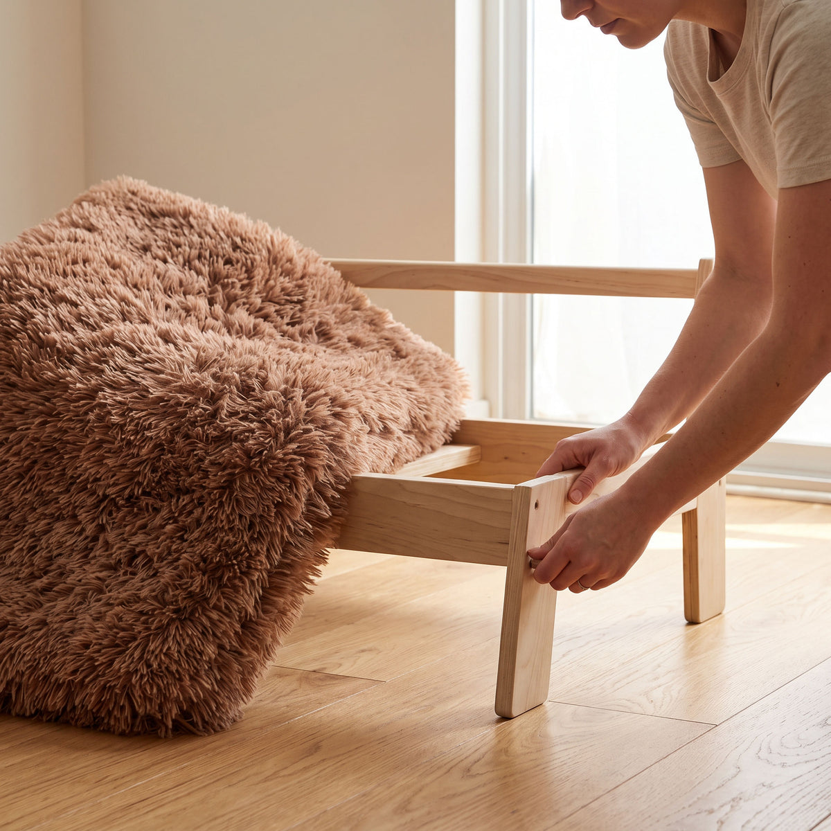 Hands twisting the last wooden leg into the cat sofa frame on a hardwood floor