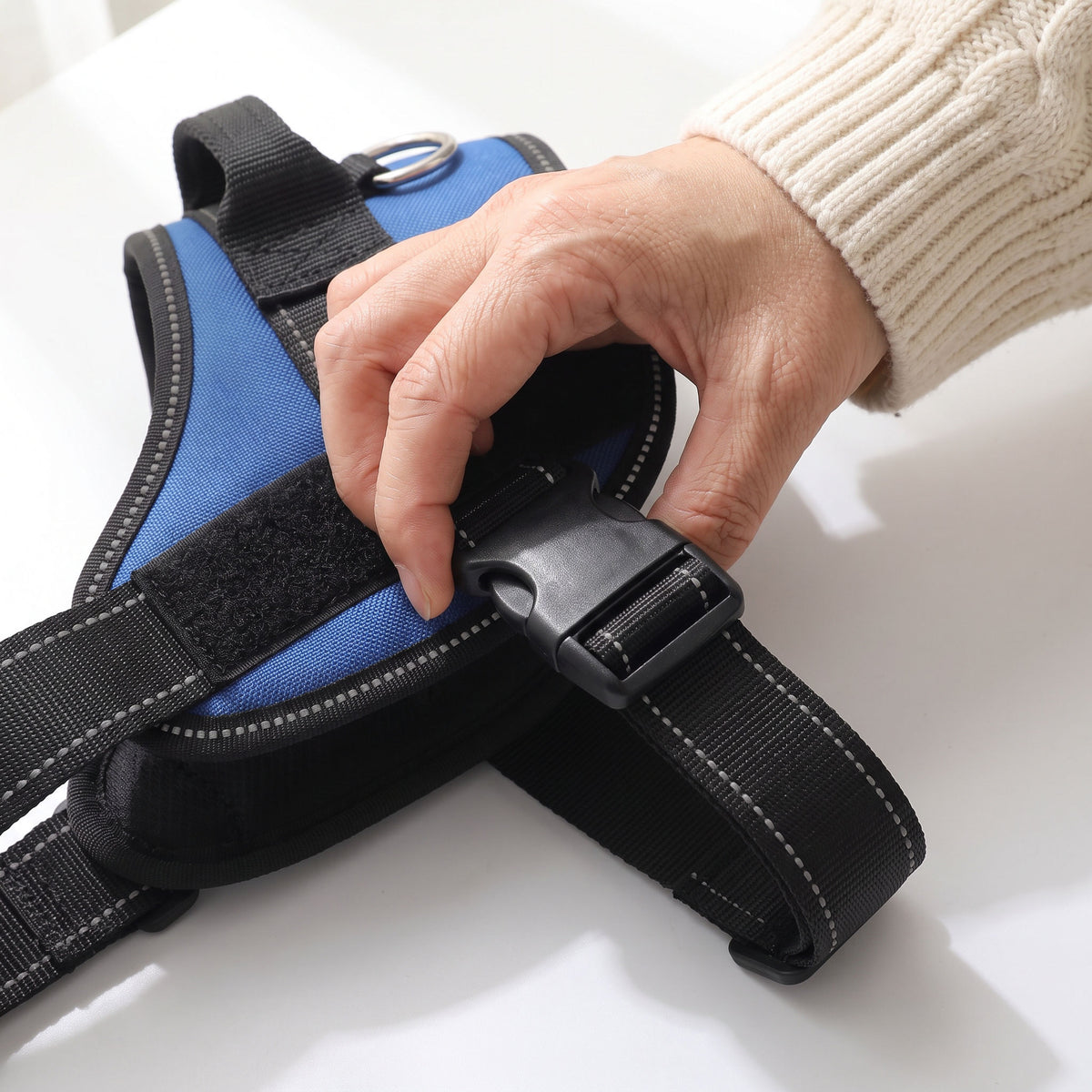 A woman's hand snapping open the chest buckle of the harness