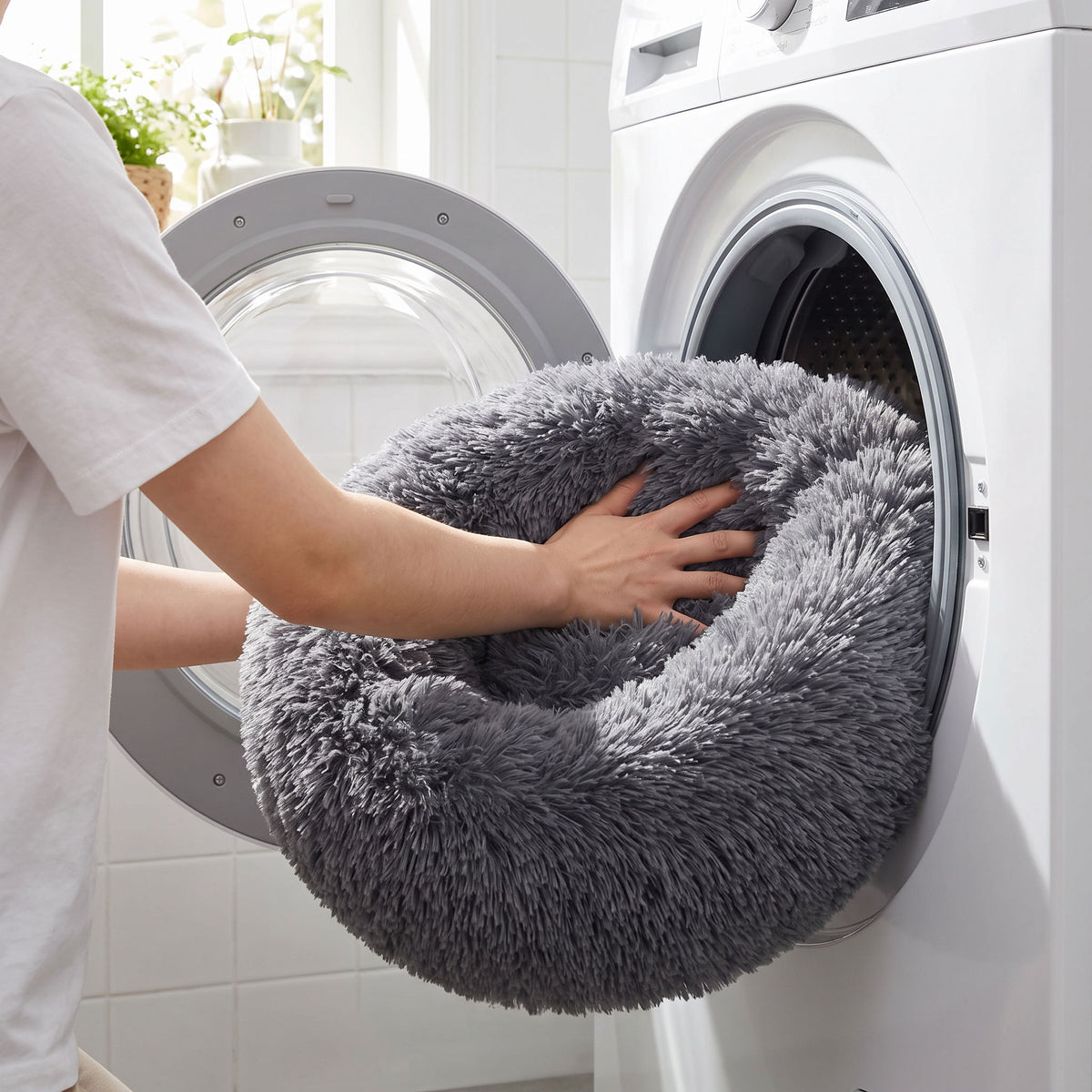 The round plush bed being loaded into a front-load washing machine